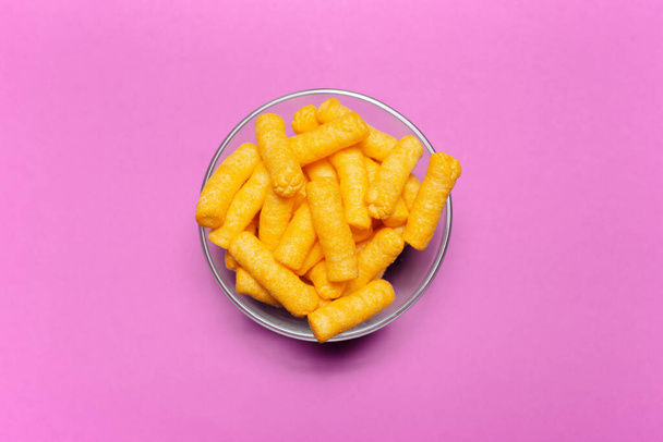 Top view of transparent bowl with corn puffs on pink background. - Fotoğraf, Görsel