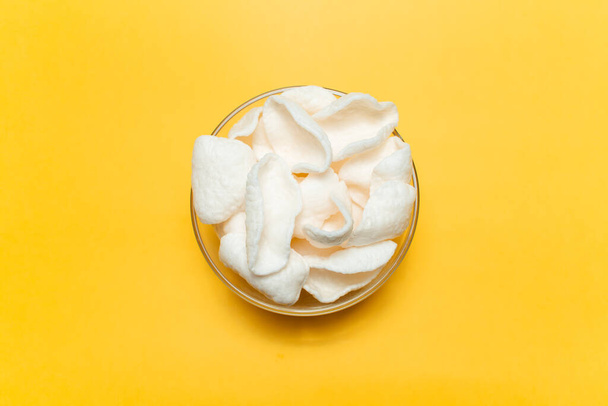 Top view of white chips in bowl on yellow background. - Foto, afbeelding