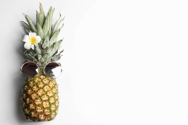 Pineapple with sunglasses and plumeria flower on white background, top view. Creative concept - Foto, Bild