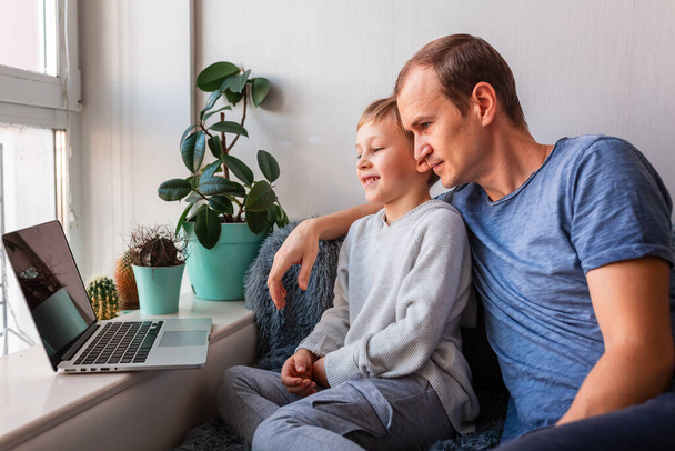 Father and son having video call with grandparents on laptop during covid quarantine lockdown. Stay at home, distance communication concept - Foto, Imagen