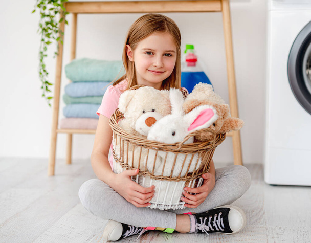 Little girl holding toys in washing basket - Фото, зображення