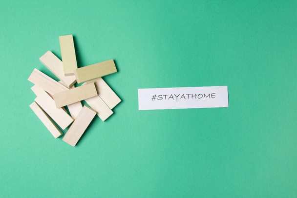 jenga wooden blocks and hashtag stay at home on green colored paper background. - Photo, image