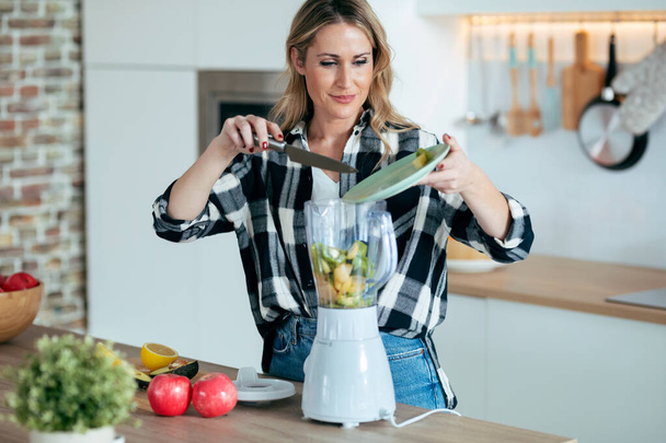 Shot of pretty mature woman mixing fruit in blender for fresh breakfast in the kitchen at home. - Valokuva, kuva