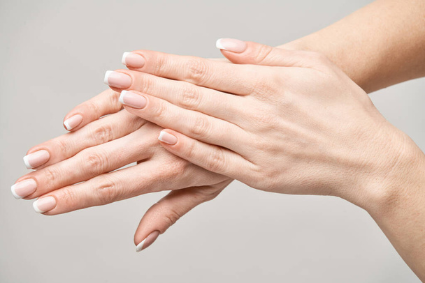 Beautiful Female Hands with French manicure over light grey background - Foto, immagini