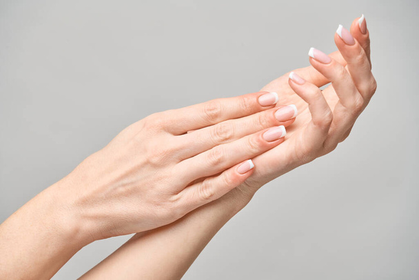 Beautiful Female Hands with French manicure over light grey background - Fotoğraf, Görsel