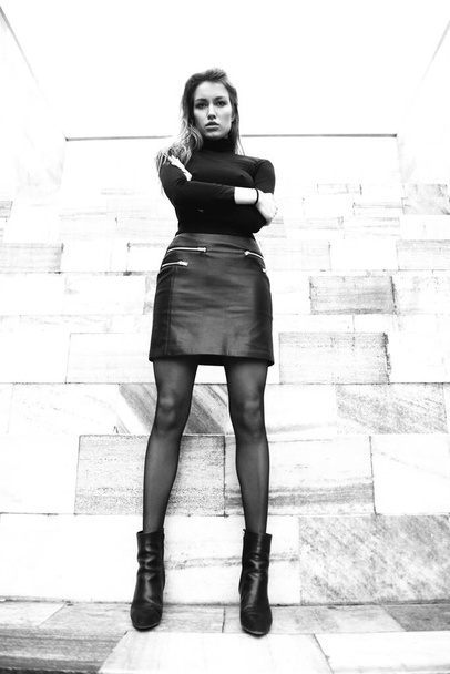 Fashion model. Young blond caucasian woman dressed in black clothes. Beautiful caucasian girl posing outdoor in Milan, Italy. Street fashion. Black and white. - 写真・画像