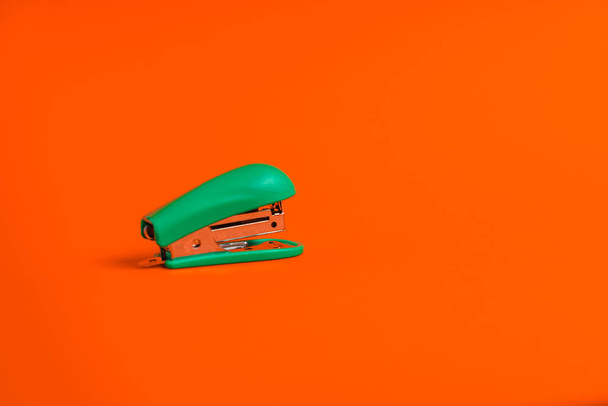 Канцелярский степлер на оранжевом фоне. Минимализм и копировальное пространство - Фото, изображение