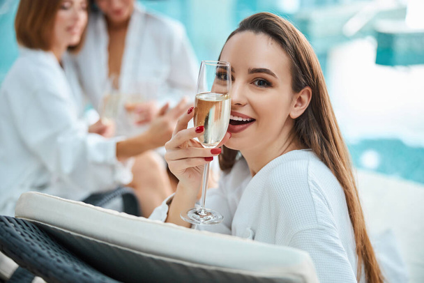 Happy young woman posing with champagne glass by the pool - Photo, image