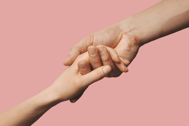 helpende hand - steun, bijstand en liefdadigheidsconcept. handen samen te reiken op roze achtergrond - Foto, afbeelding