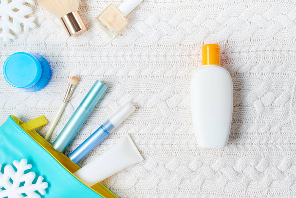 winter flat lay with cosmetics, sunscreen bottle and snowflake on white knitted background. - Fotó, kép