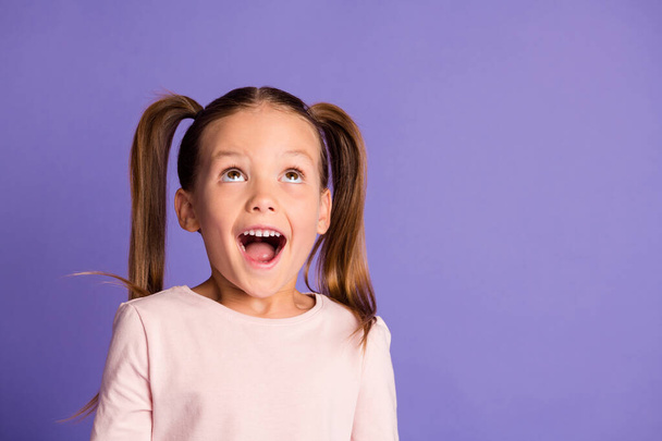 Photo of amazed pretty little girl wear sweatshirt look up empty space isolated on purple color background - Foto, Imagem