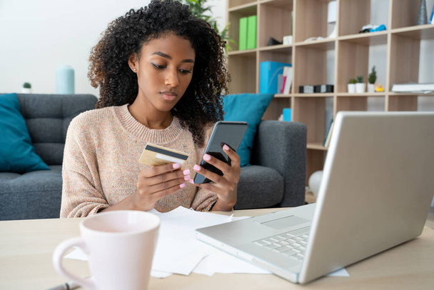 Siyah bir kadın banka kartıyla online alışveriş yapıyor. - Fotoğraf, Görsel