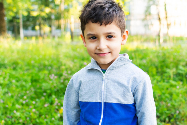 portret van een 6-jarige jongen in het park in de zomer - Foto, afbeelding