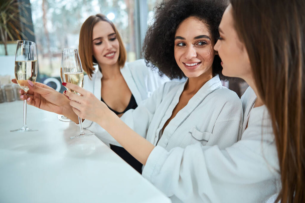 Szczęśliwe młode kobiety stojące i trzymające szampana - Zdjęcie, obraz