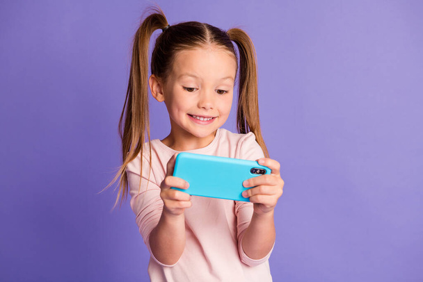 Photo of brown haired pigtails small girl hold play phone wear sweatshirt isolated on violet color background - Photo, image