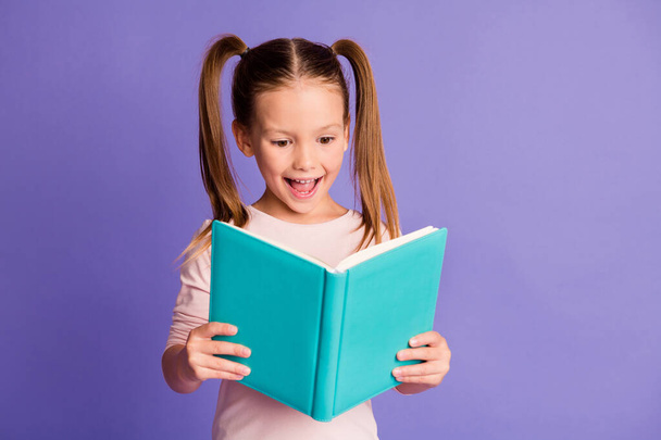 Photo of optimistic happy little girl hold read book study wear pullover isolated on violet color background - Photo, Image