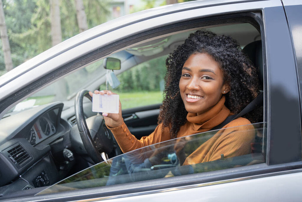 Czarna kobieta trzyma prawo jazdy do swojego pierwszego nowego samochodu. Zadowolenie klienta - Zdjęcie, obraz