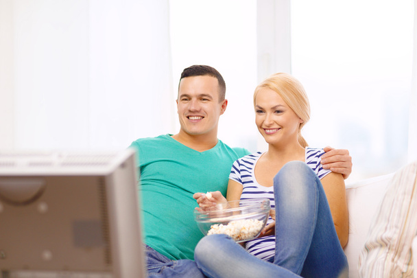 Smiling couple with popcorn watching movie at home - Фото, изображение