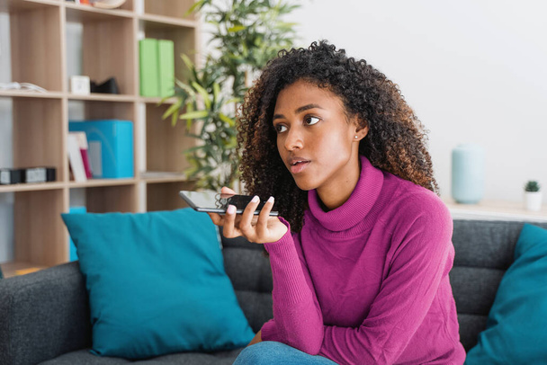 Rento nuori musta nainen rentouttava kotona tekstiviestejä älypuhelimella - Valokuva, kuva