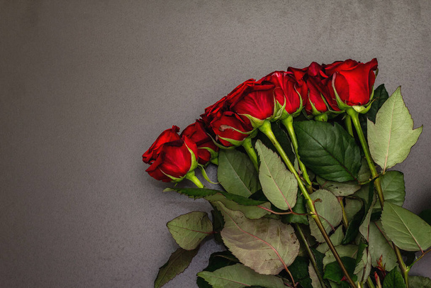 Bouquet of fresh burgundy roses on a black stone concrete background. Fragrant red flowers, gift concept for Valentine's Day, Wedding or Birthday - 写真・画像