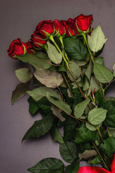 Μπουκέτο με φρέσκα τριαντάφυλλα μπορντό σε μαύρο φόντο από μπετόν. Αρωματικά κόκκινα λουλούδια, ιδέα για δώρο για την Ημέρα του Αγίου Βαλεντίνου, Γάμος ή Γενέθλια - Φωτογραφία, εικόνα