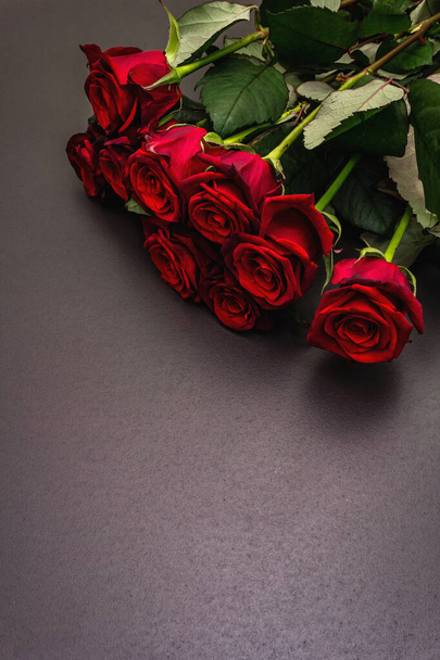 Bouquet of fresh burgundy roses on a black stone concrete background. Fragrant red flowers, gift concept for Valentine's Day, Wedding or Birthday - Photo, Image