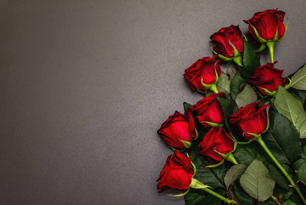 Bouquet of fresh burgundy roses on a black stone concrete background. Fragrant red flowers, gift concept for Valentine's Day, Wedding or Birthday - 写真・画像