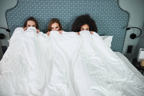 Three best girlfriends enjoying bedtime and looking at camera - Valokuva, kuva