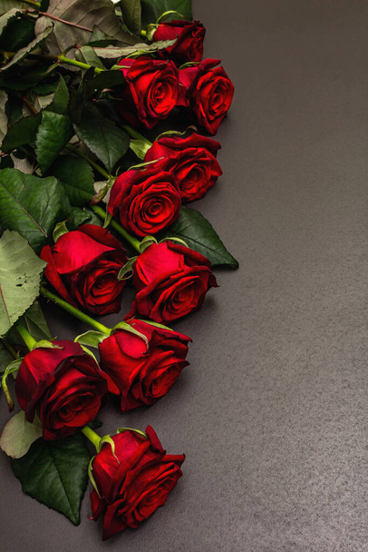 Bouquet of fresh burgundy roses on a black stone concrete background. Fragrant red flowers, gift concept for Valentine's Day, Wedding or Birthday - Photo, Image