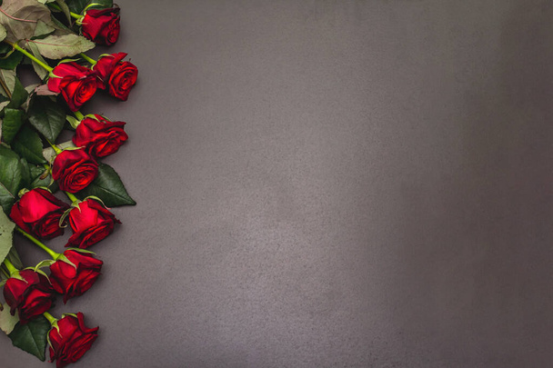 Boeket van frisse bordeaux rozen op een zwarte steen betonnen achtergrond. Geurige rode bloemen, cadeau concept voor Valentijnsdag, Bruiloft of Verjaardag - Foto, afbeelding
