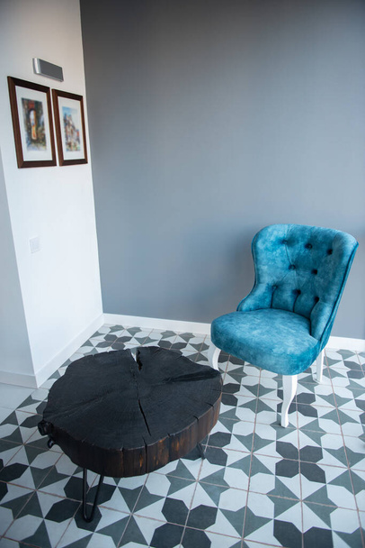 Modern design home interior with elegant blue chair in retro style and black wooden coffee table over gray wall. Stylish home decor - Photo, image
