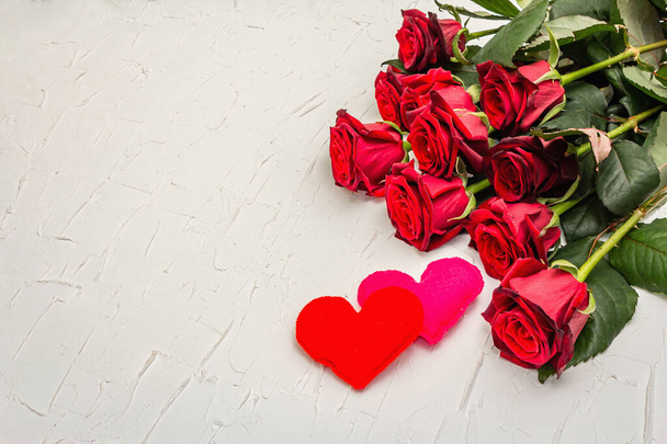 Свіжі бургундські троянди з відчутими серцями на білому килимку. Червоні квіти, подарунки на День святого Валентина, весілля або день народження. - Фото, зображення