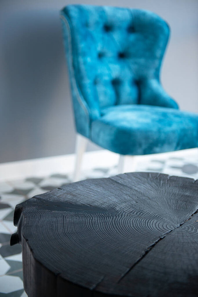 Interior de la casa de diseño moderno con elegante silla azul en estilo retro y mesa de centro de madera negra sobre pared gris. Elegante decoración para el hogar - Foto, Imagen