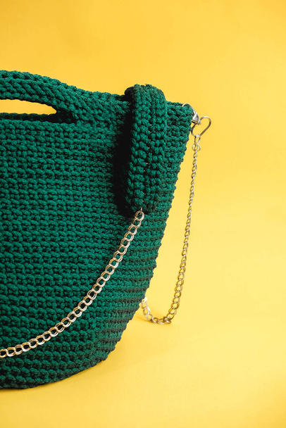 Elegante bolso de punto verde para mujer sobre fondo amarillo. Copiar, espacio vacío para texto. - Foto, Imagen