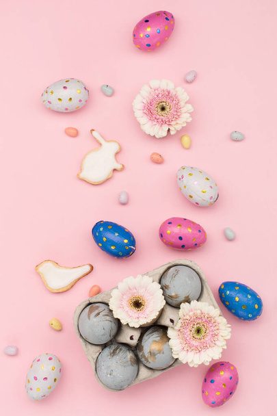 Happy Easter holiday greeting card. Homemade Easter sugar cookies, chocolate eggs, flowers on pastel pink background. Festive Easter breakfast concept. Copy space, top view. - Photo, Image