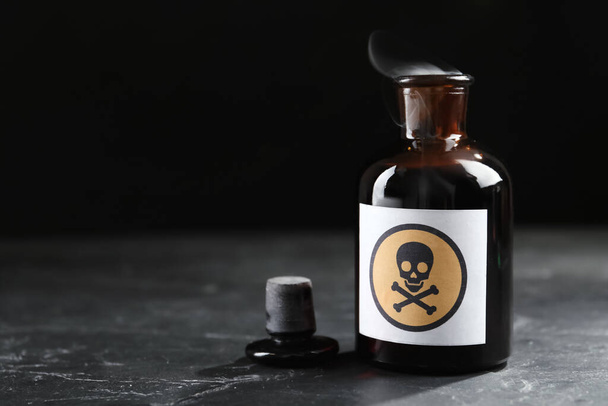 Open glass bottle of smoking poison with warning sign on black table. Space for text - Foto, Imagem