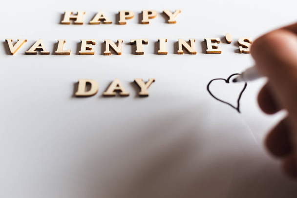 Szczęśliwych Walentynek pisane drewnianymi literami na białym tle. Ręczne rysowanie kształtu serca.  - Zdjęcie, obraz