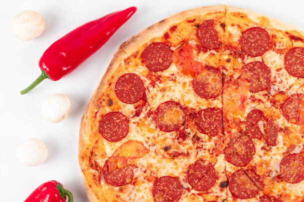 frische aromatische italienische Pfefferoni-Pizza mit Mozzarella, Paprika und Pilzen auf weißem Holztischhintergrund - Foto, Bild