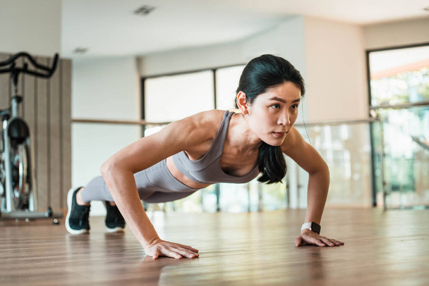 Beautiful young Asian woman doing push ups in the gym - Fotografie, Obrázek