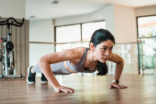Beautiful young Asian woman doing push ups in the gym - Valokuva, kuva