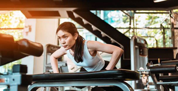 Beautiful young Asian woman doing push ups in the gym - Photo, Image