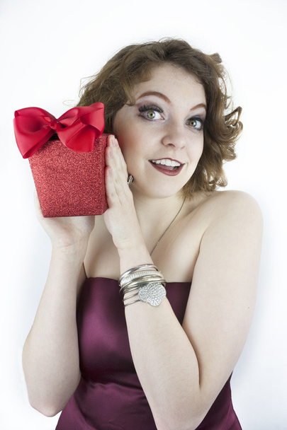 Söpö nuori nainen, jolla on punainen, kimalteleva lahjapakkaus jousella
 - Valokuva, kuva
