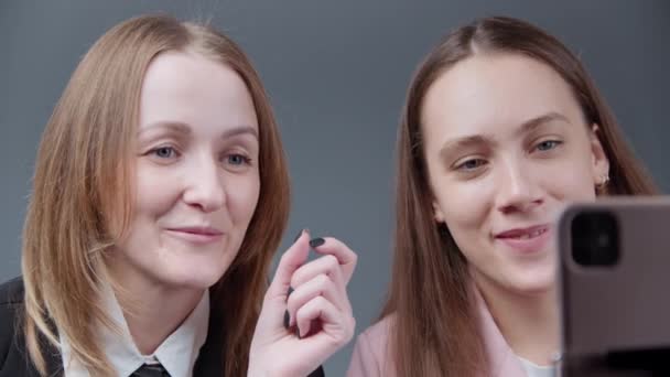 Video van twee meisjes bloggers praten met volgers op grijze achtergrond - Video
