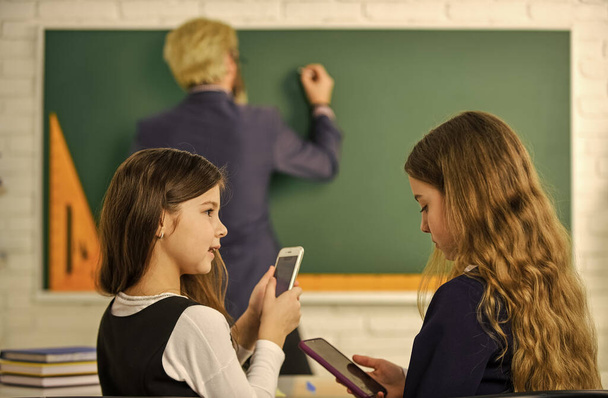 Concentrated on studying. Students Studying And Reading. homework writing and reading. children girls and teacher man. Elementary School Teacher Giving Support In Classroom. Pupil Wearing Uniform - Foto, immagini