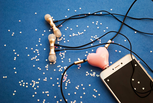 Beautiful background with hearts for Valentine's day, heart shaped headphone splitter. A smartphone and two pairs of headphones connected through an adapter.  - Photo, Image