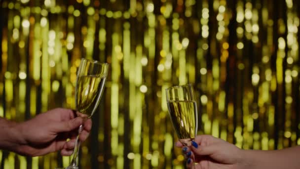 Duas mãos com copos de vinho de champanhe ou coquetel fazendo saudações, levantando brinde no fundo de ouro - Filmagem, Vídeo