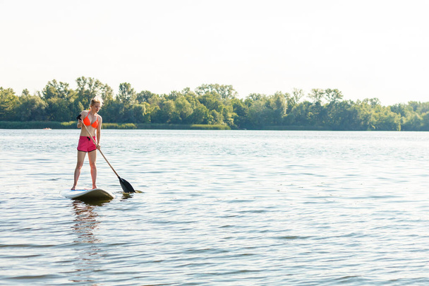 Jovem mulher atraente em pé paddle board no lago, SUP - Foto, Imagem