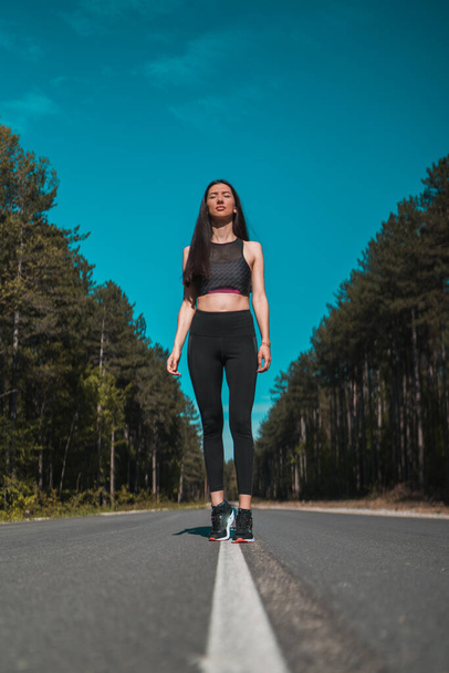 Young Fit athletic female jogger in black sportswear posing outdoors - Photo, Image