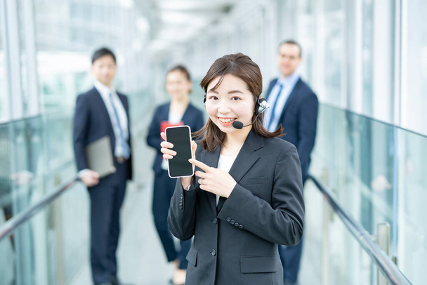 Επιχειρηματίας φορώντας ακουστικά και δείχνοντας σε ένα smartphone - Φωτογραφία, εικόνα