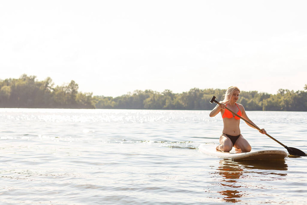A beautiful woman practicing paddle on a beautiful sunny day - Photo, Image